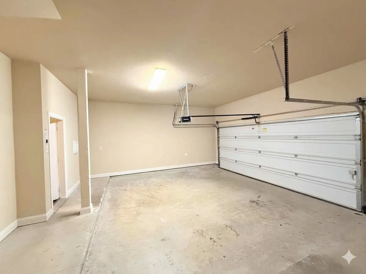 Spacious garage featuring a concrete floor, white painted walls, and a sectional overhead door