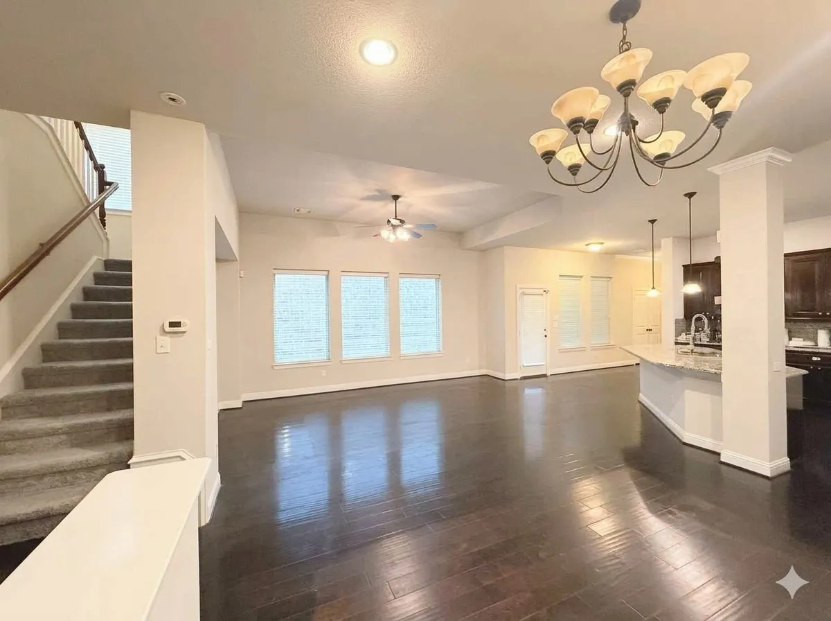 Wood-finish flooring throughout the main living area, complemented by a large decorative chandelier and recessed lighting