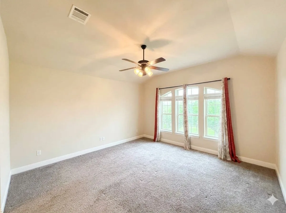 Vaulted ceiling, ceiling fan with integrated lighting, three large arched windows, light-toned carpeting, and neutral wall paint