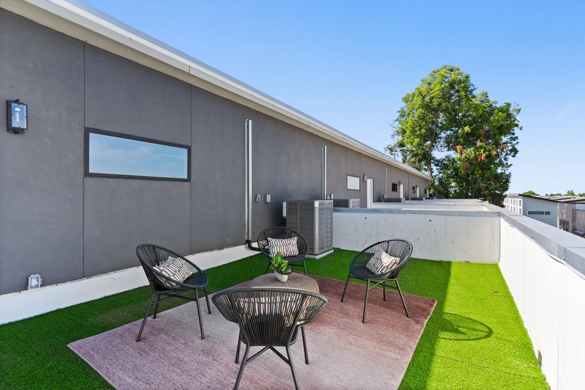 Rooftop deck featuring artificial turf, a low concrete wall, and a horizontal window