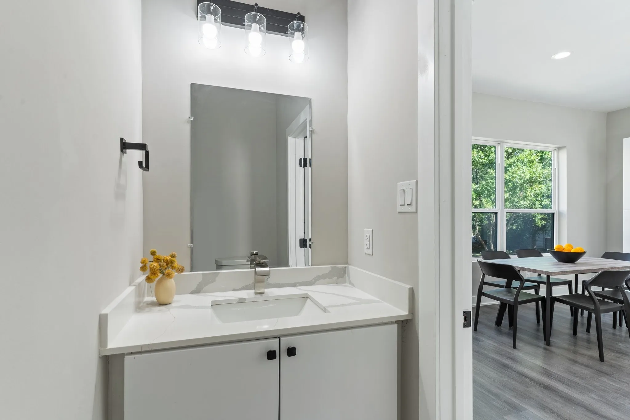 White vanity with a single basin sink, white countertop, and brushed nickel faucet