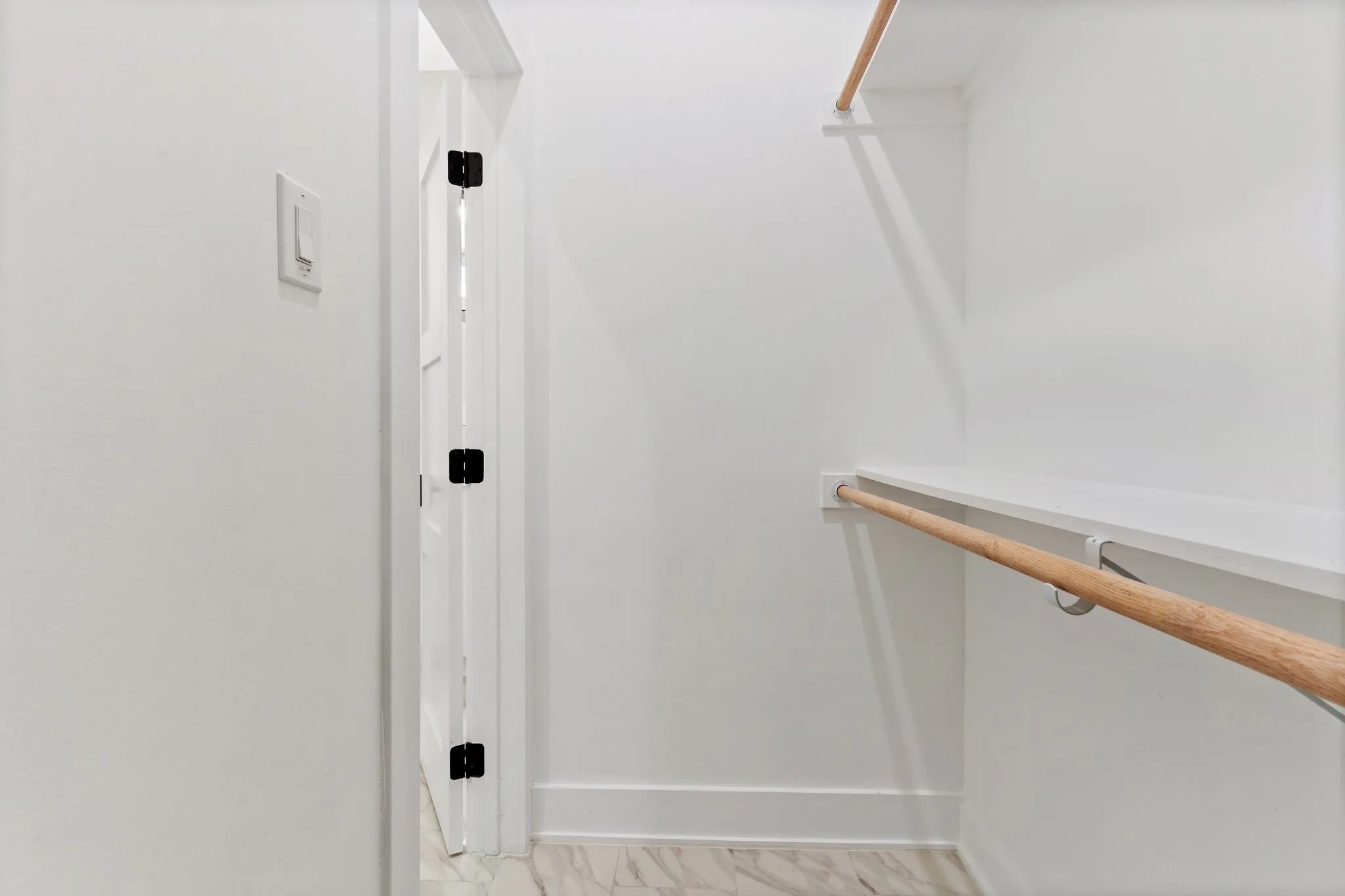 White walls with wood-finish hanging rods, built-in shelving, and a patterned floor