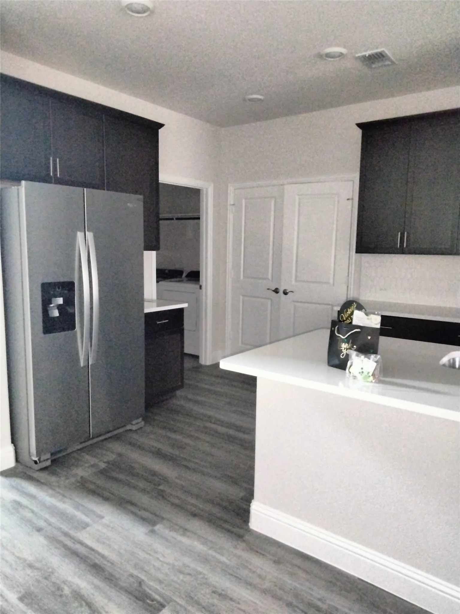 Wood-finish flooring, dark cabinetry, white countertops, recessed lighting, and a double-door entry