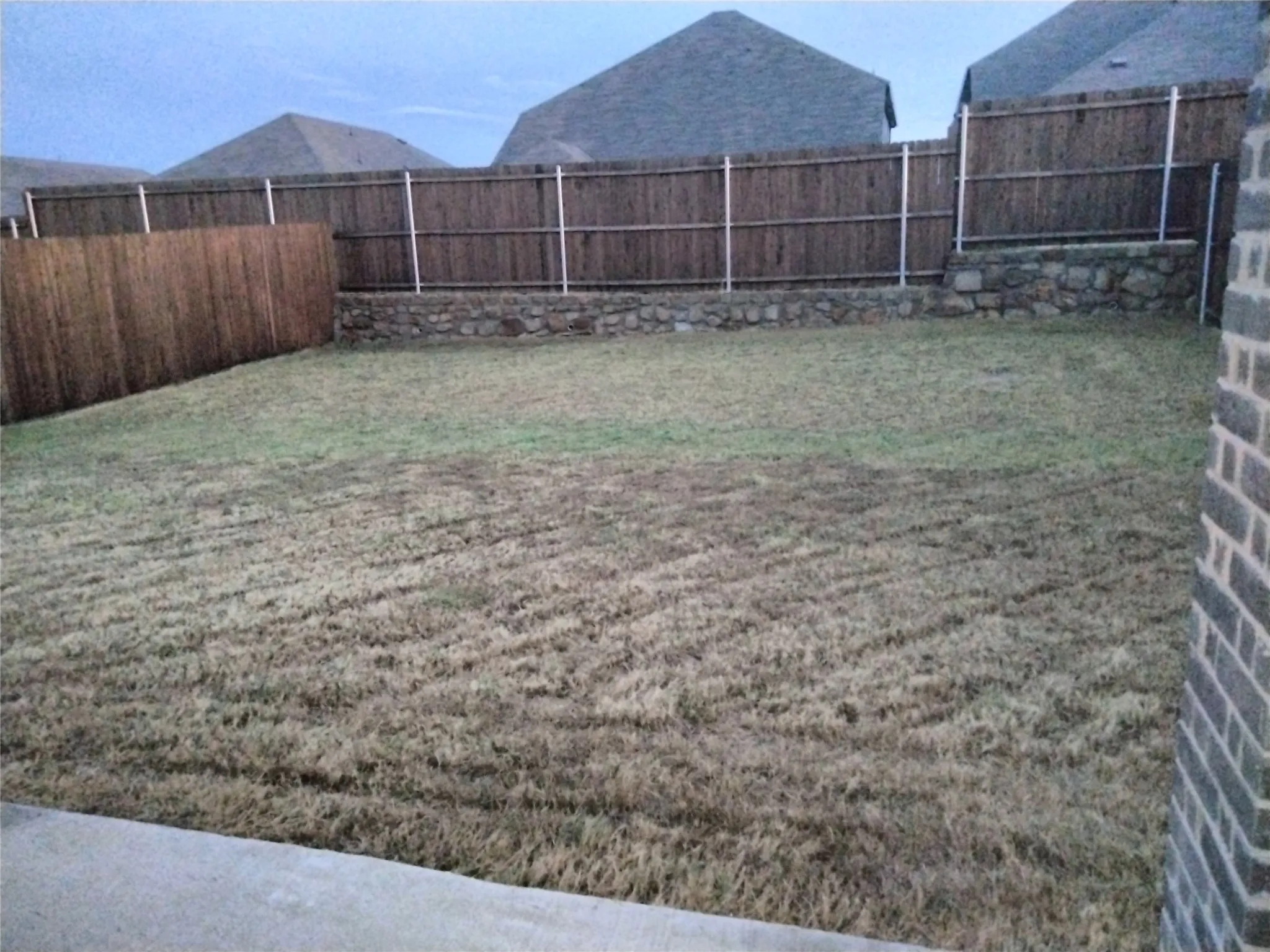 Expansive backyard space with a wood privacy fence and a stone retaining wall