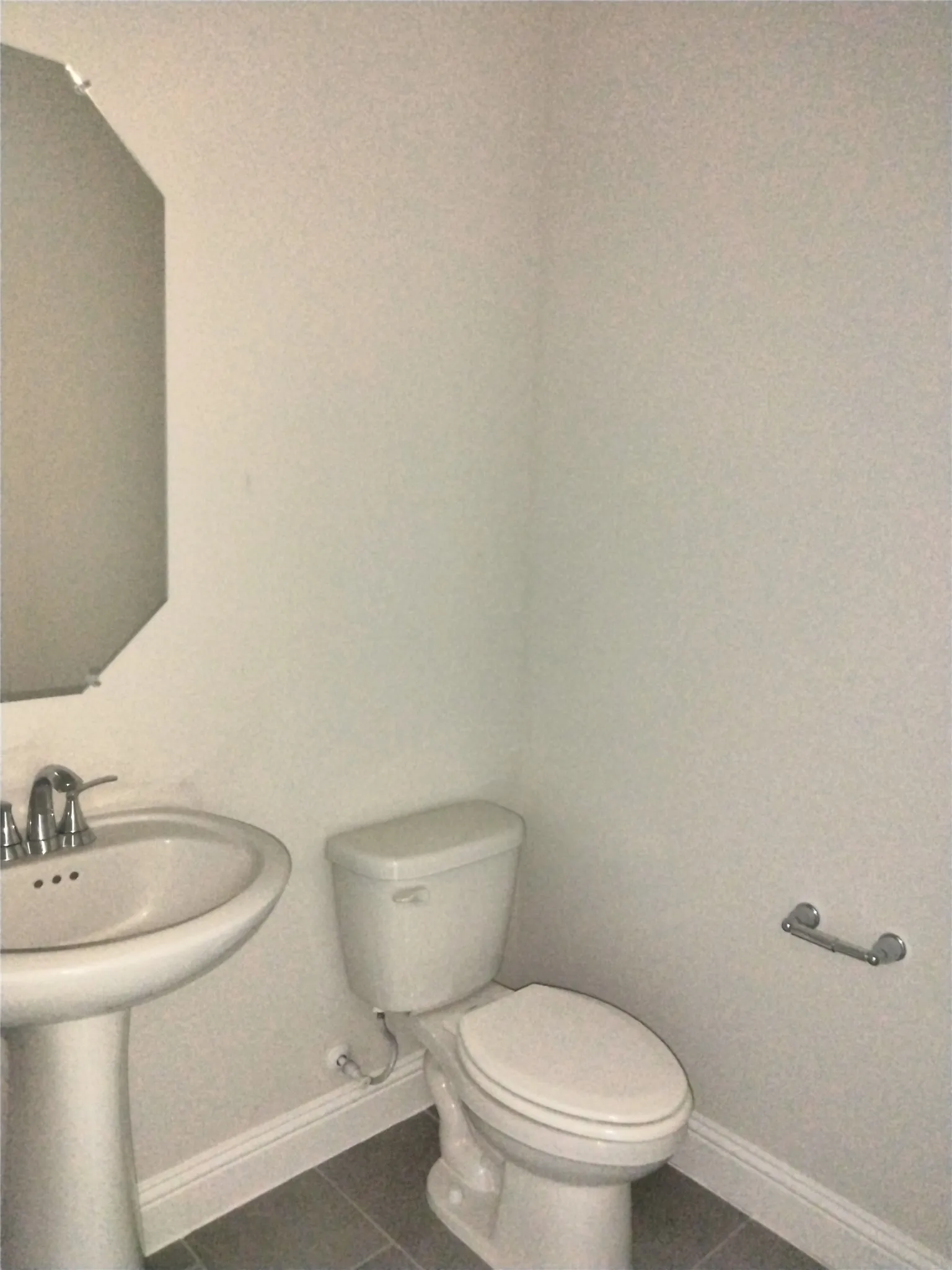 Pedestal sink with chrome-finish faucet, toilet, and gray tile flooring