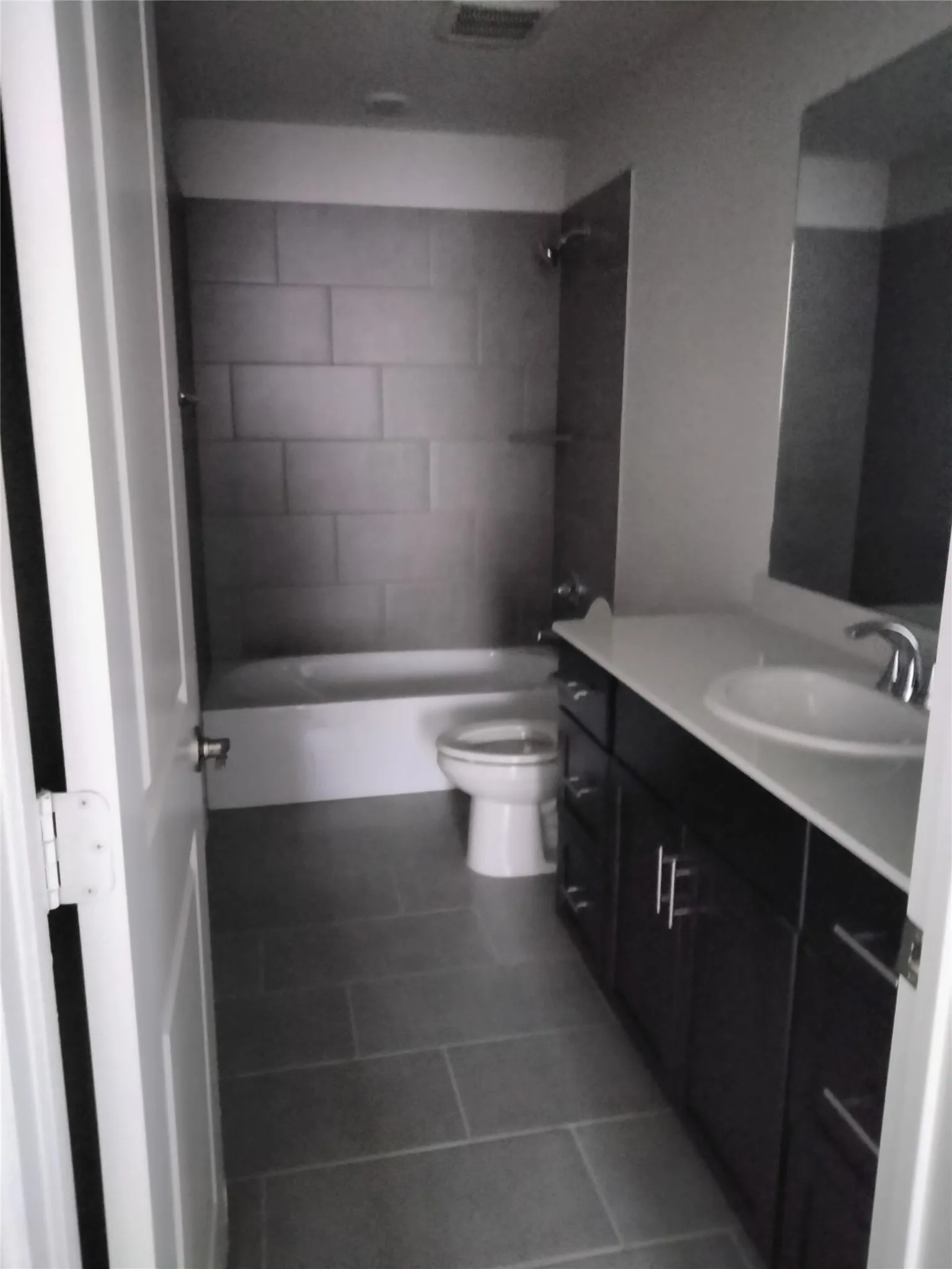 Bathroom featuring a spacious vanity with white countertop, integrated sink, and dark wood-finish cabinetry