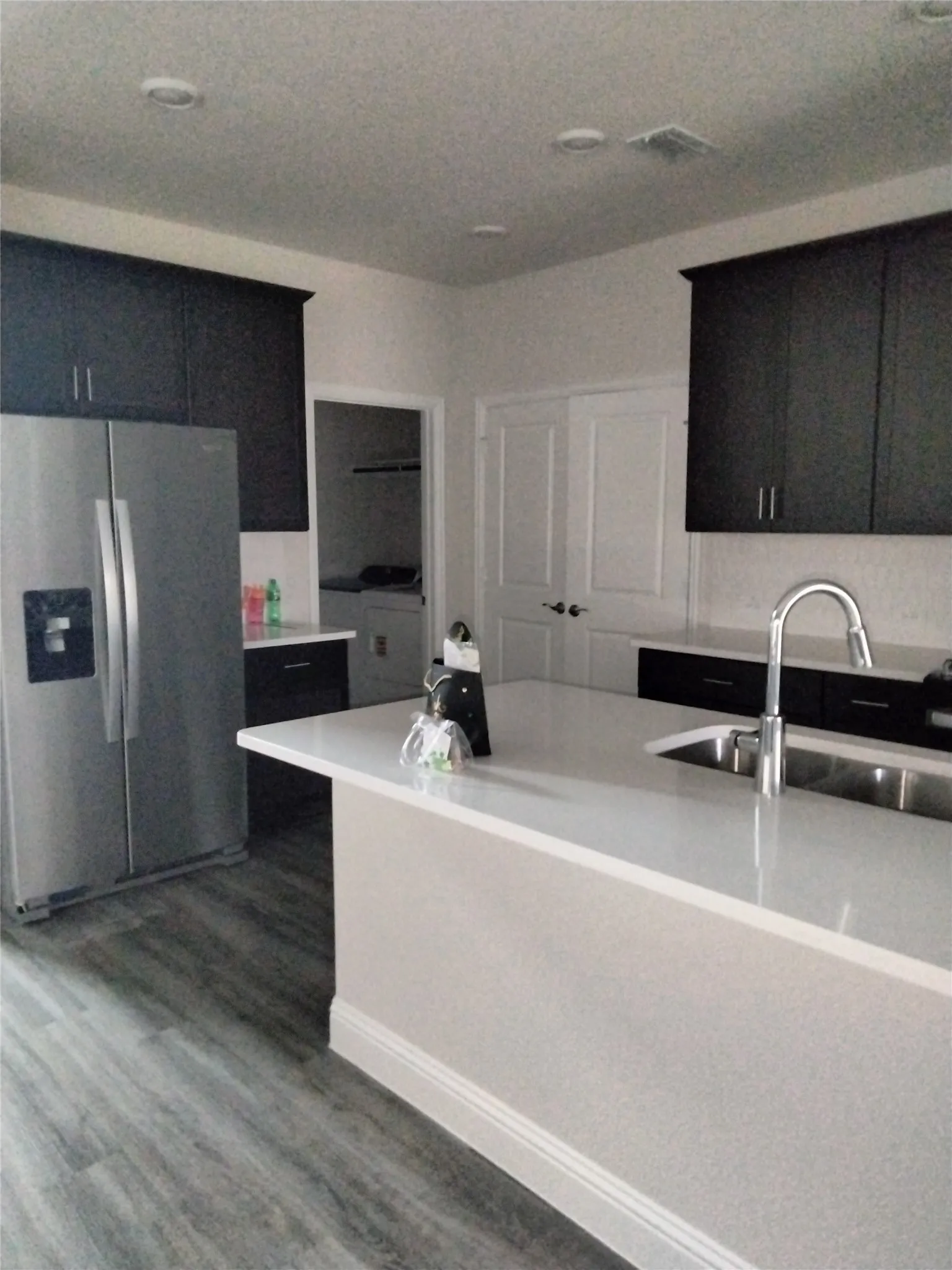Kitchen featuring a center island, stainless steel refrigerator, dark wood-finish cabinetry, and a stainless steel sink with a high-arc faucet