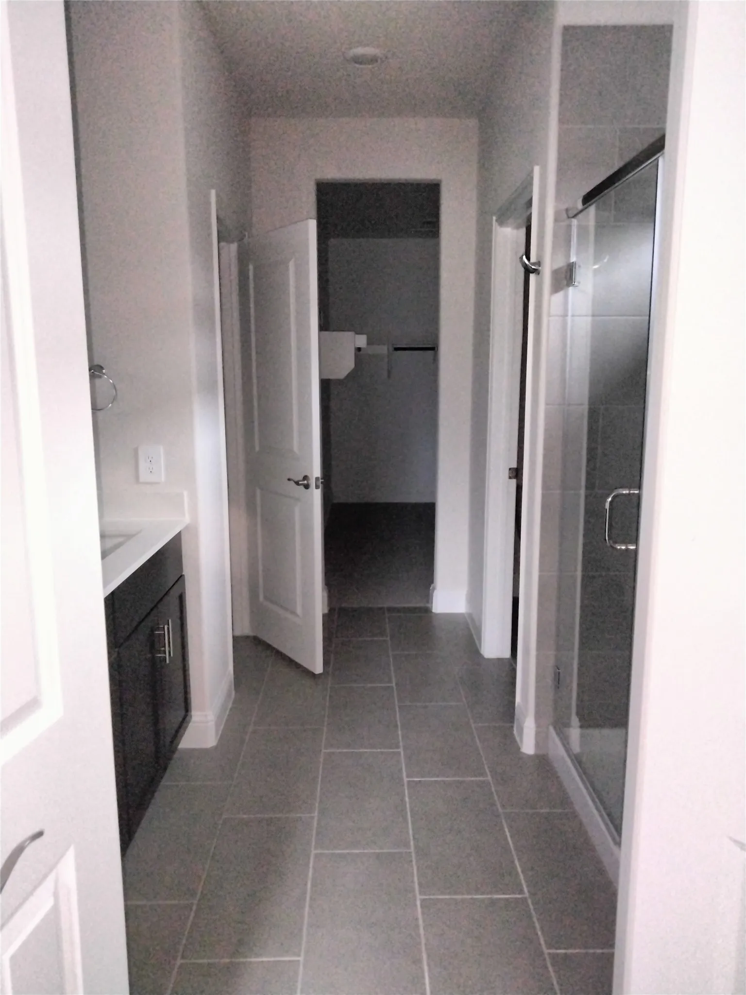 Tile flooring, dark wood-finish vanity, white countertop, glass-enclosed shower, recessed lighting
