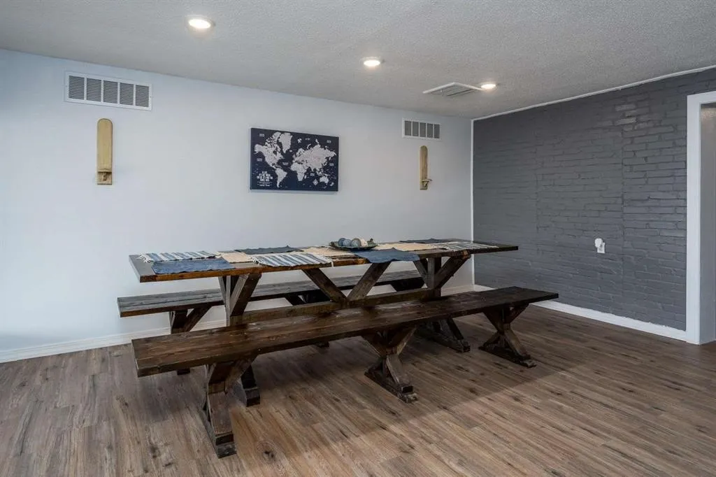 Wood-finish flooring, recessed lighting, and a textured brick accent wall