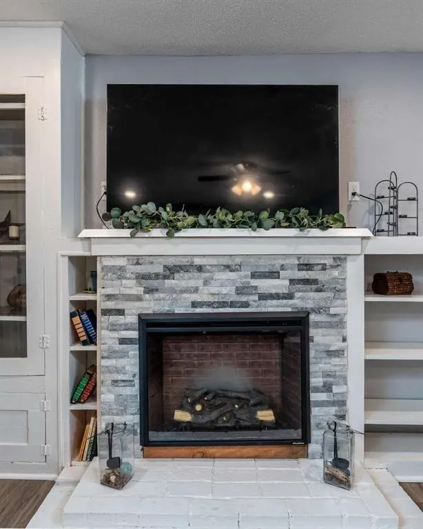 Fireplace featuring a stacked stone surround, white mantel, and brick-lined firebox