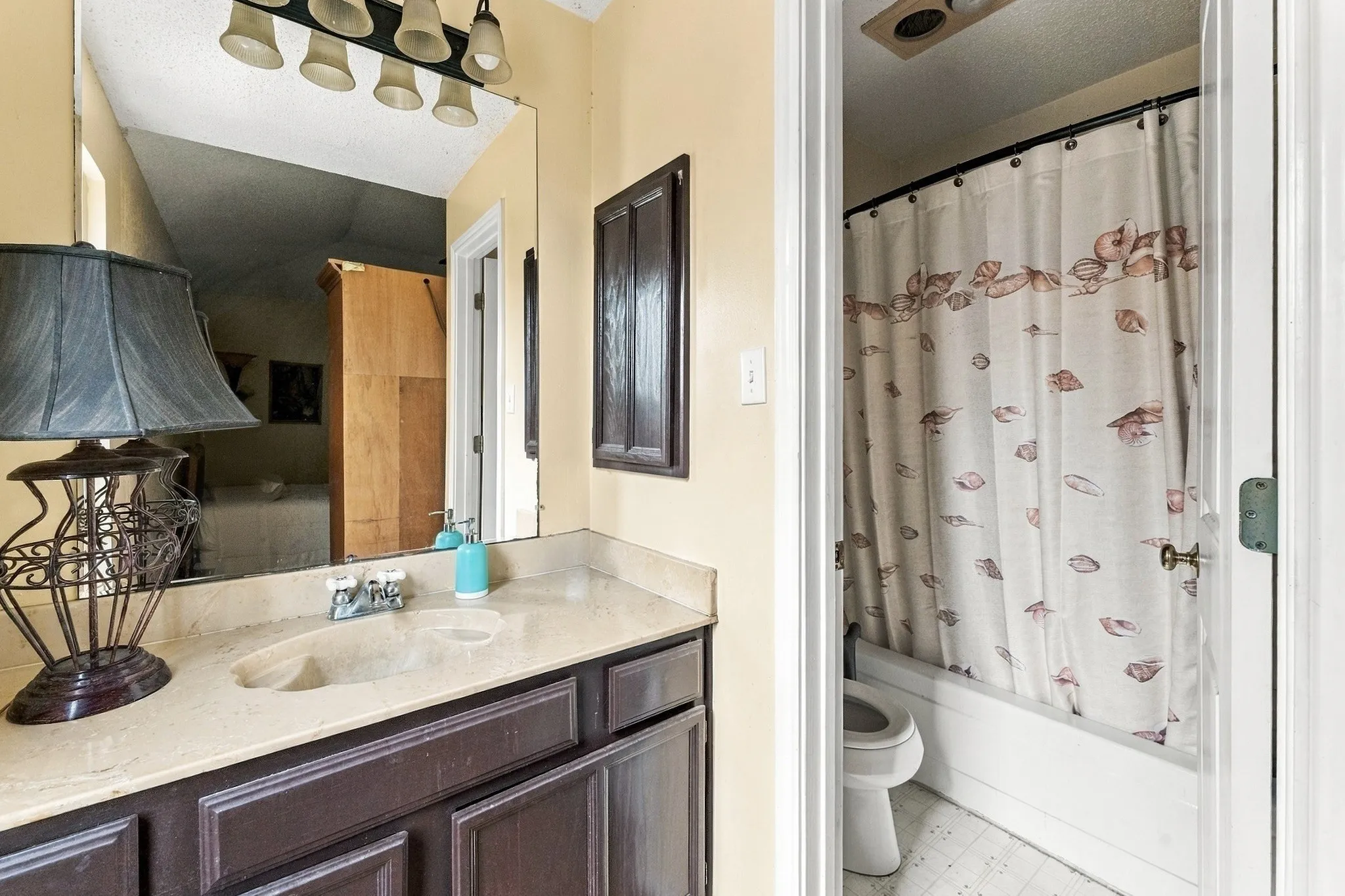 Vanity with an integrated sink, broad wall mirror, and overhead light fixture