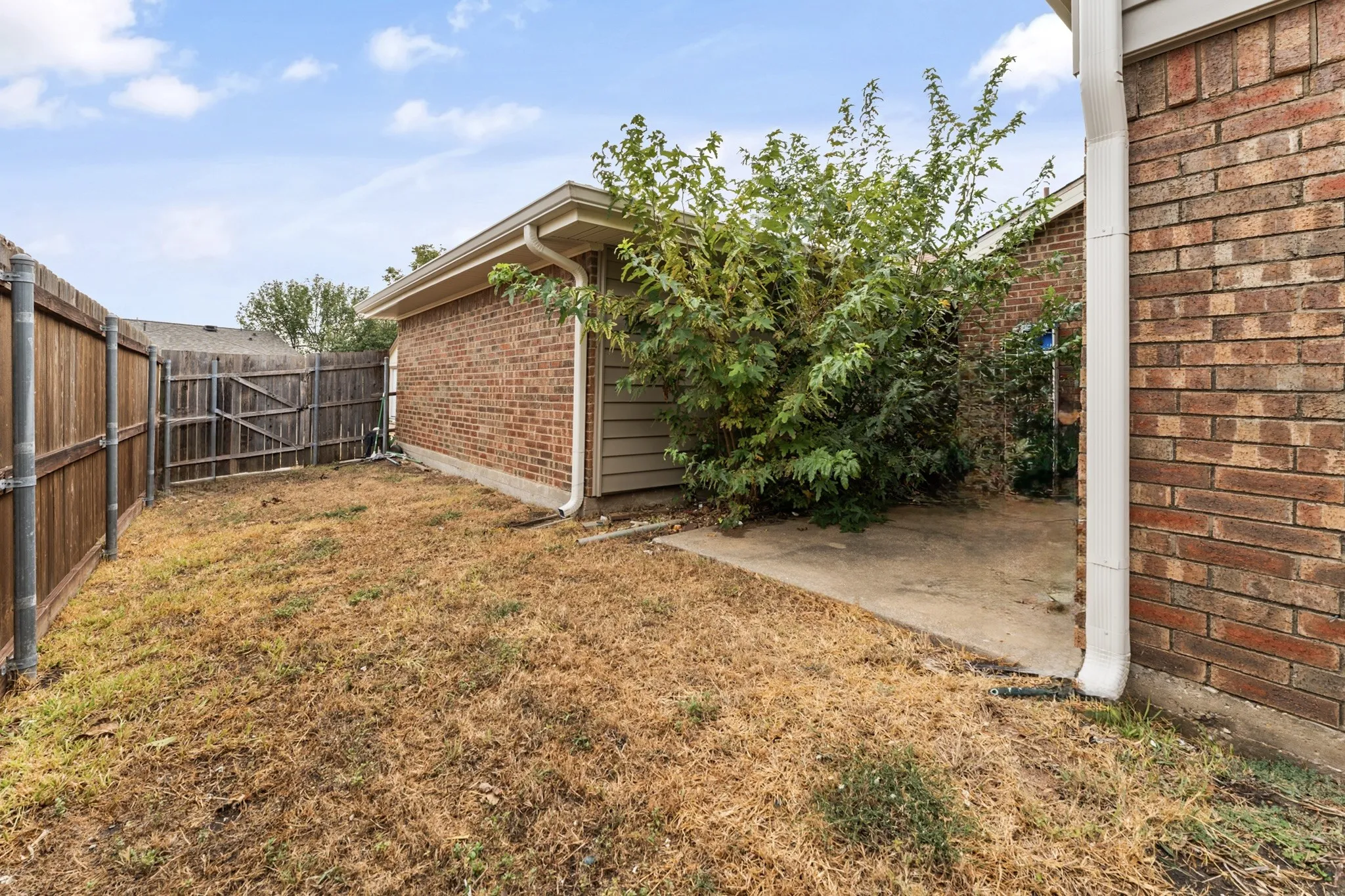 Private fenced yard featuring a brick exterior and a concrete patio