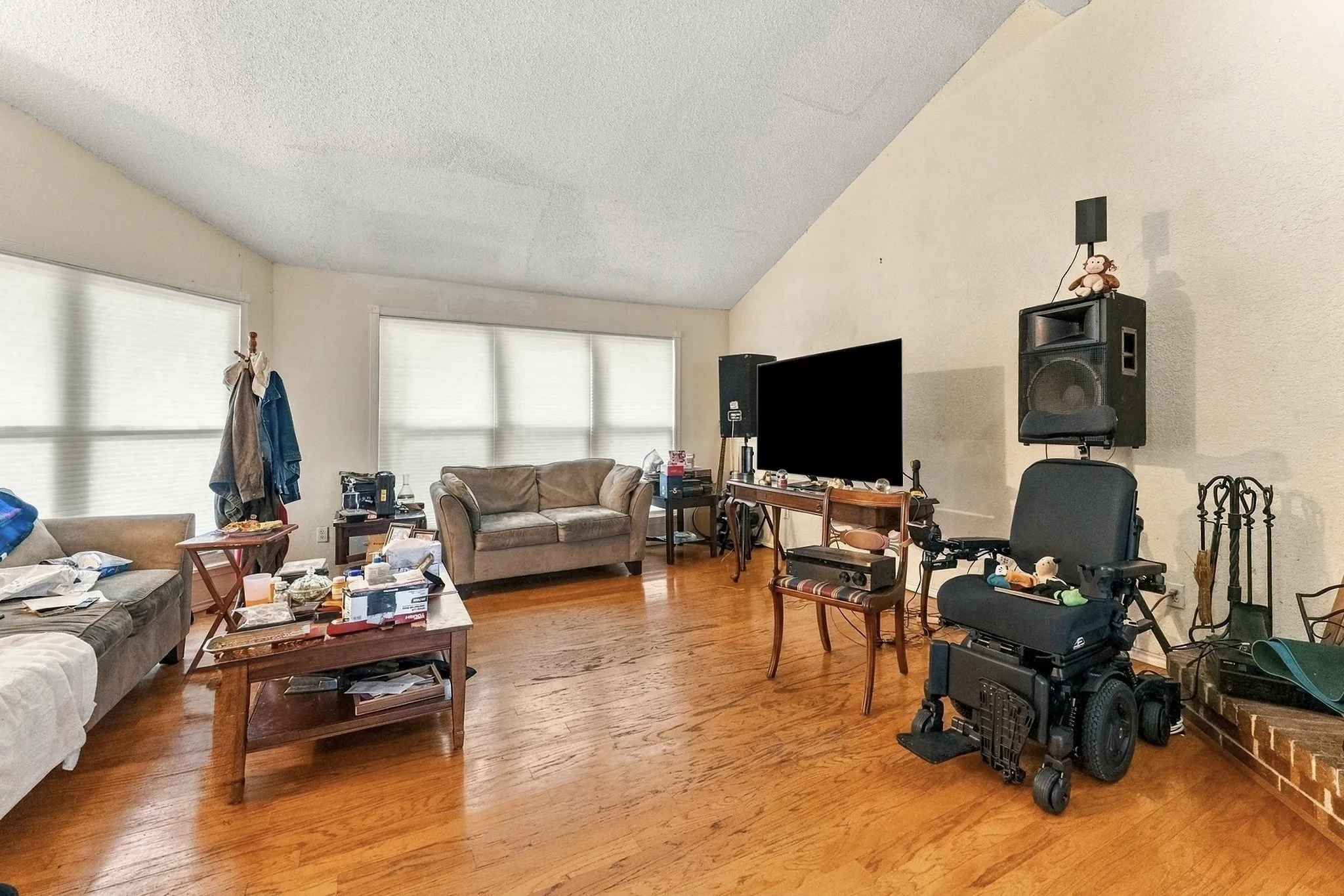 Wood-finish flooring, vaulted ceiling, and multiple windows with blinds