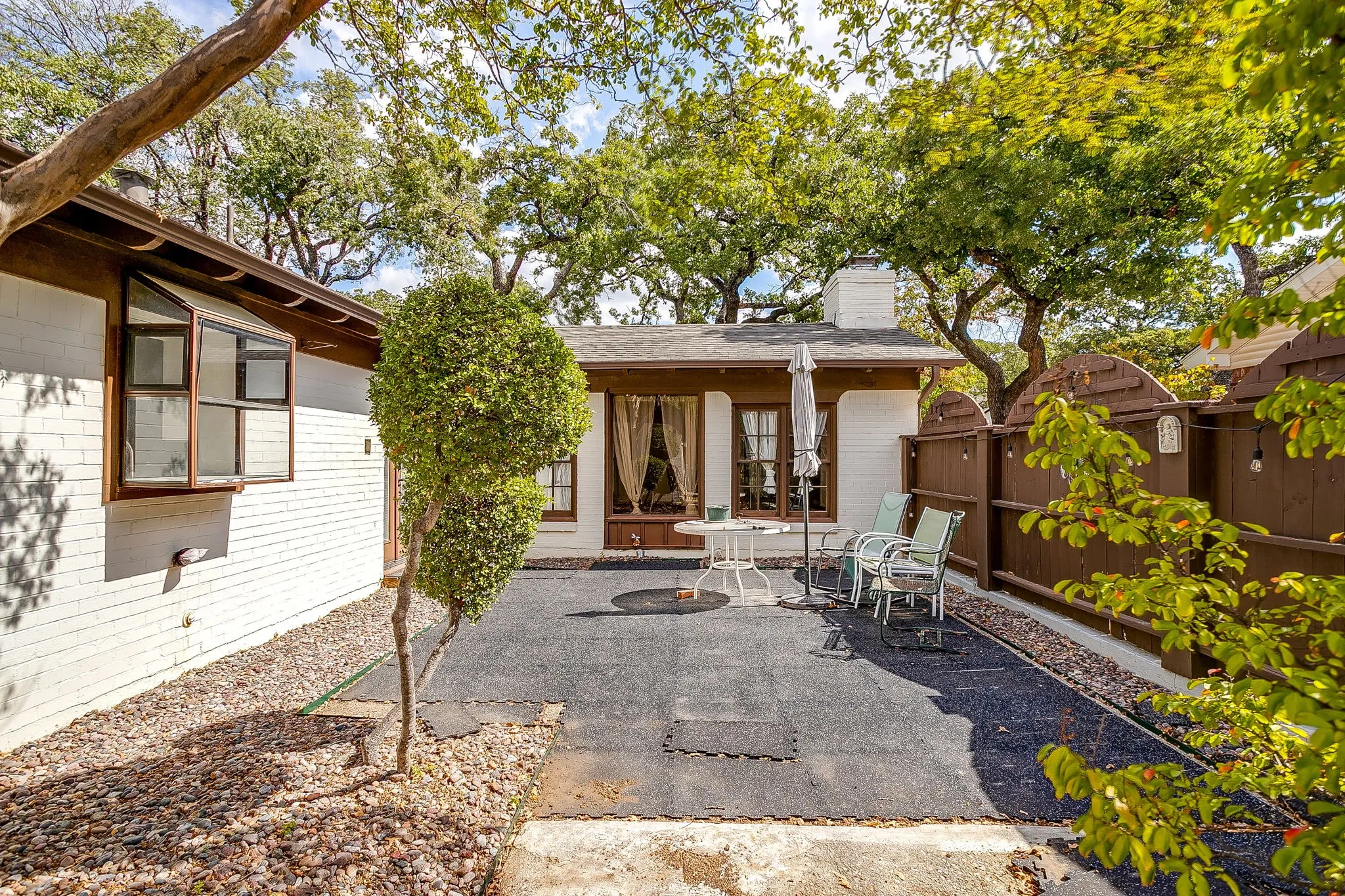 Private patio space featuring a solid privacy fence and mature trees