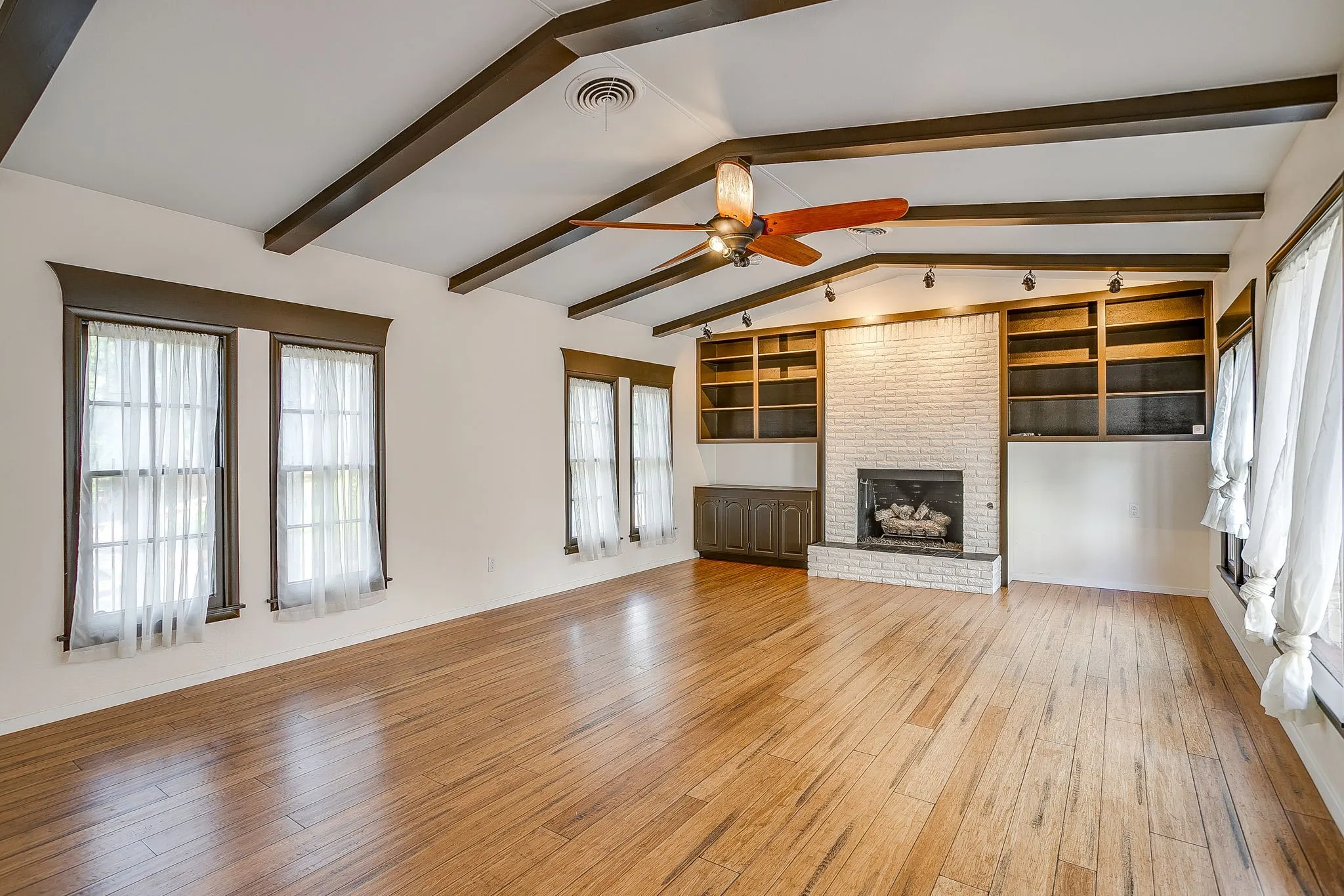 Wood-finish flooring with exposed ceiling beams and a ceiling fan