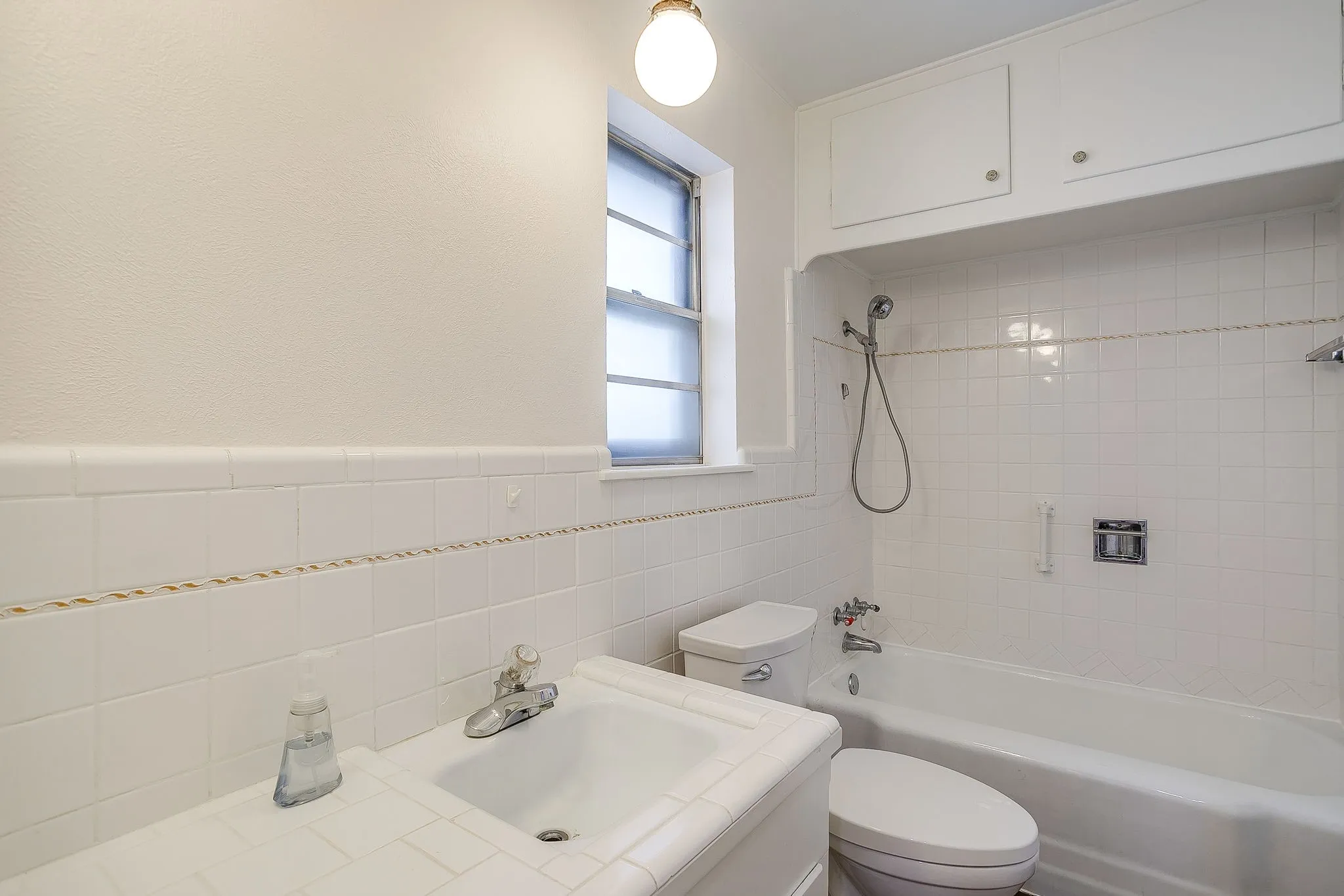 White tile shower and tub surround with integrated storage cabinetry