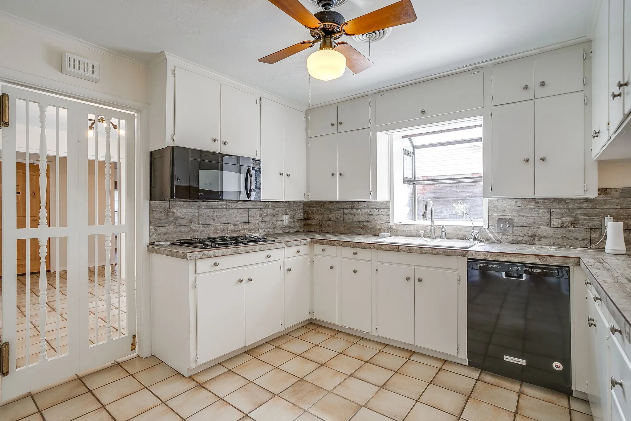 Kitchen featuring white cabinetry, tile flooring, built-in microwave, gas range, and a dishwasher