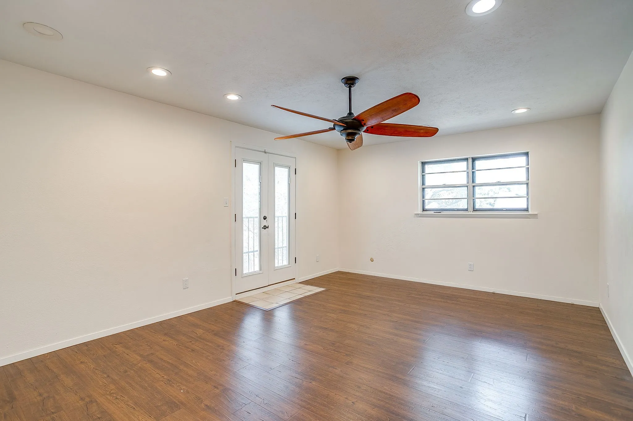 Wood-finish flooring, recessed lighting, and a ceiling fan with wood-tone blades