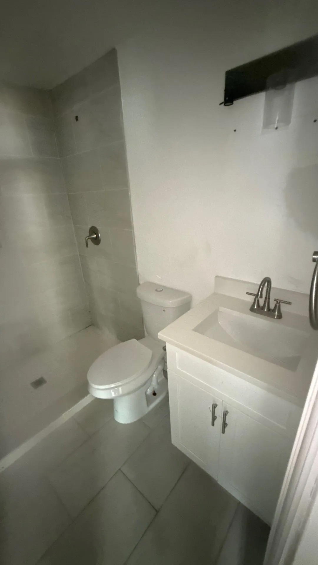 Integrated shower with tiled walls, white vanity with integrated sink, chrome faucet, and tile flooring