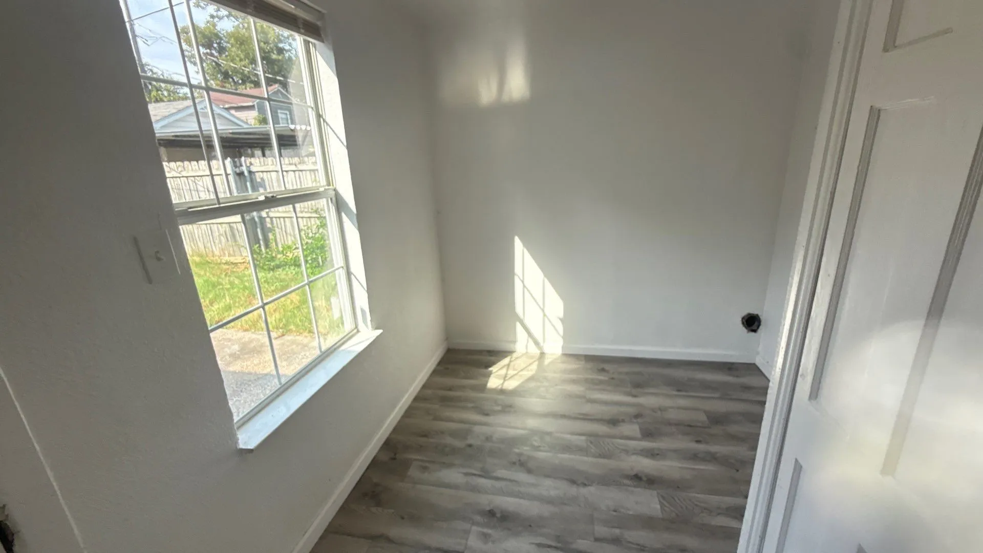 Wood-finish flooring, white walls, and a multi-pane window