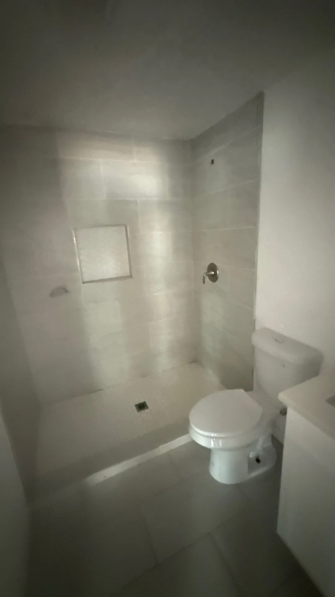 Walk-in shower with light-toned rectangular wall tiles, built-in shower niche, and a chrome shower fixture