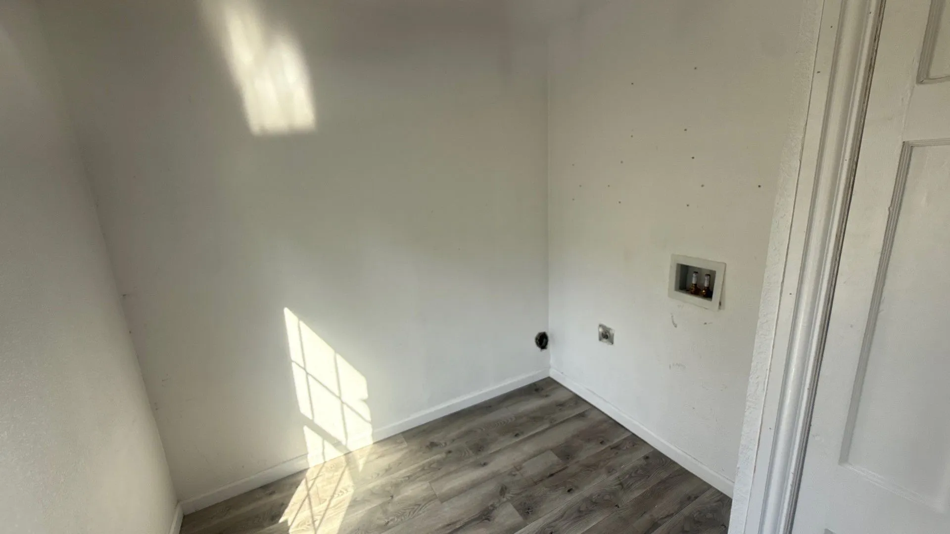 Laundry area with wood-finish flooring and white walls