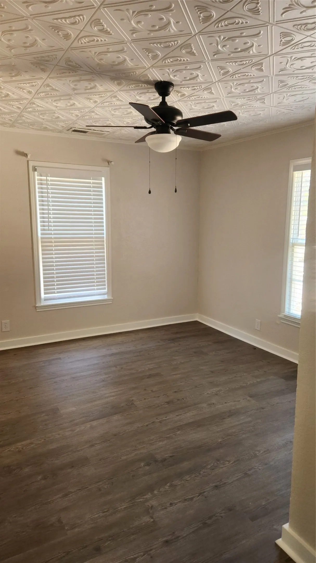 Embossed ceiling panels, wood-finish flooring, and a ceiling fan with integrated lighting