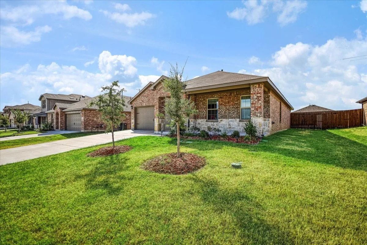 Brick exterior with stone accents, attached garage, and a fenced backyard