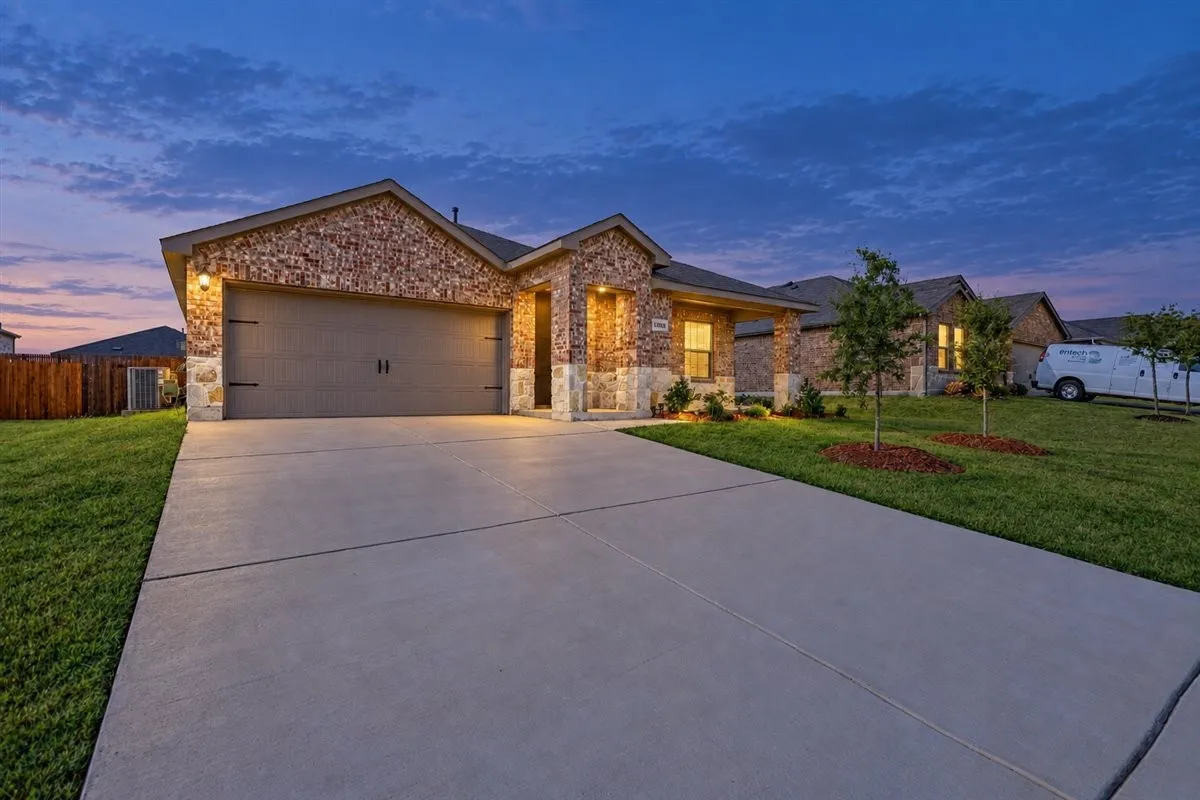 Brick and stone exterior with an attached garage, covered entryway, and concrete driveway