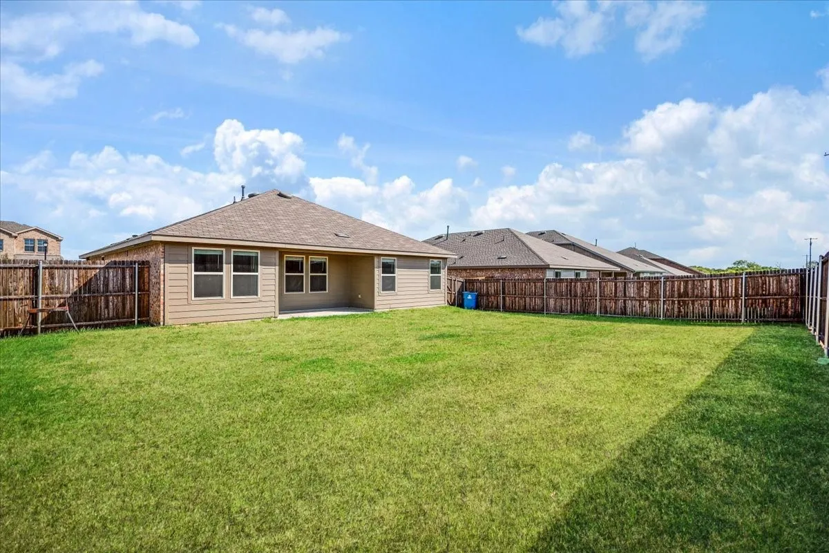 Expansive backyard featuring a manicured lawn, full wood privacy fencing, and a concrete patio