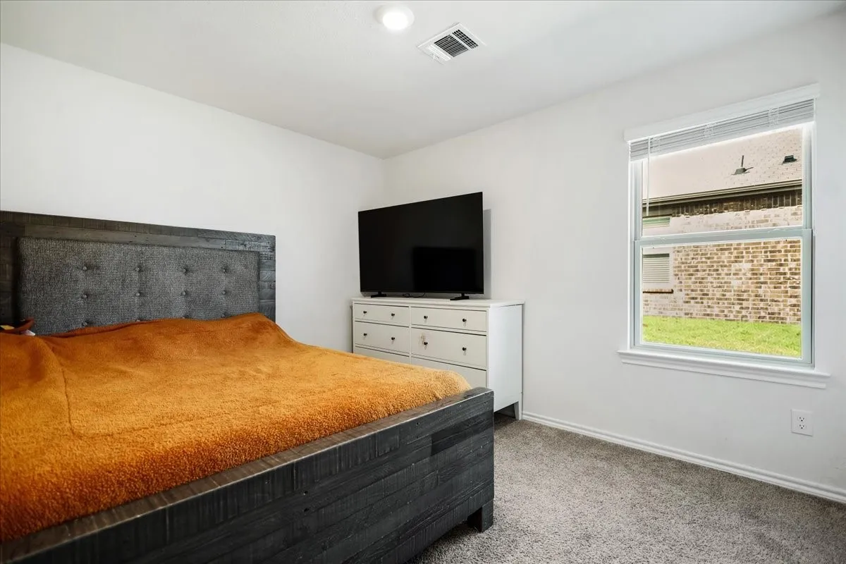 Carpeted room with a single window and white walls