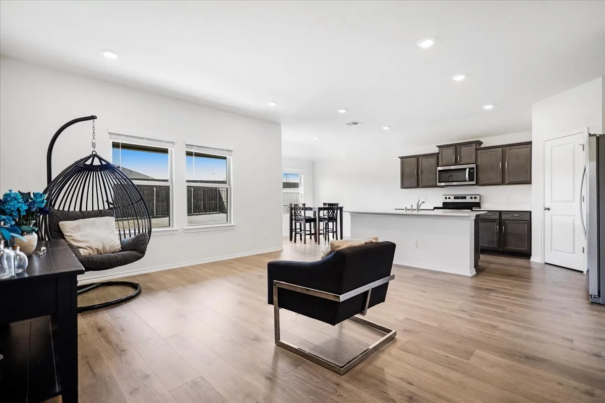 Open-concept living area with wood-finish flooring, recessed lighting, and multiple windows