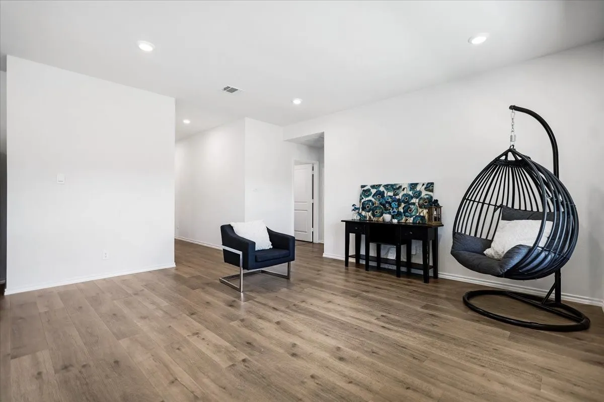 Recessed ceiling lighting, light wood-finish flooring, white painted walls, and an interior doorway