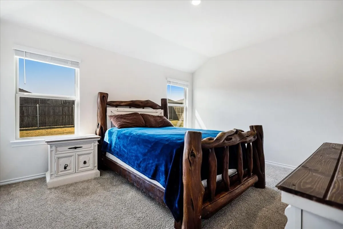 Neutral wall color, carpet flooring, multiple windows, and a vaulted ceiling