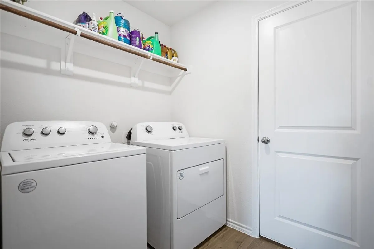 Laundry area featuring wood-finish flooring and a white paneled door