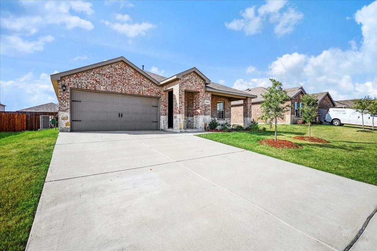 Brick and stone exterior with a covered entry, two-car garage, and a concrete driveway