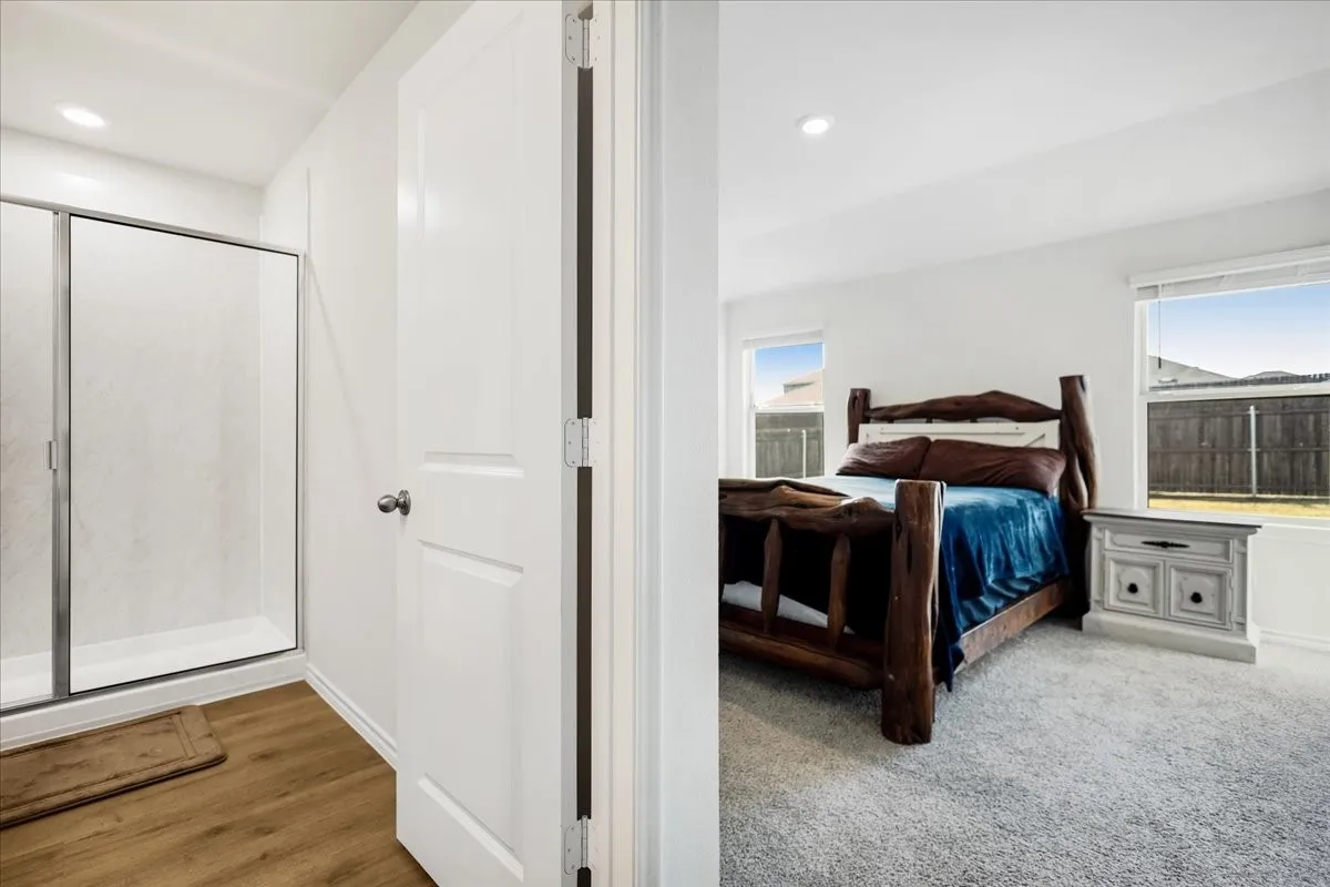 Recessed lighting, wood-finish flooring, and a glass-enclosed shower in the bathroom