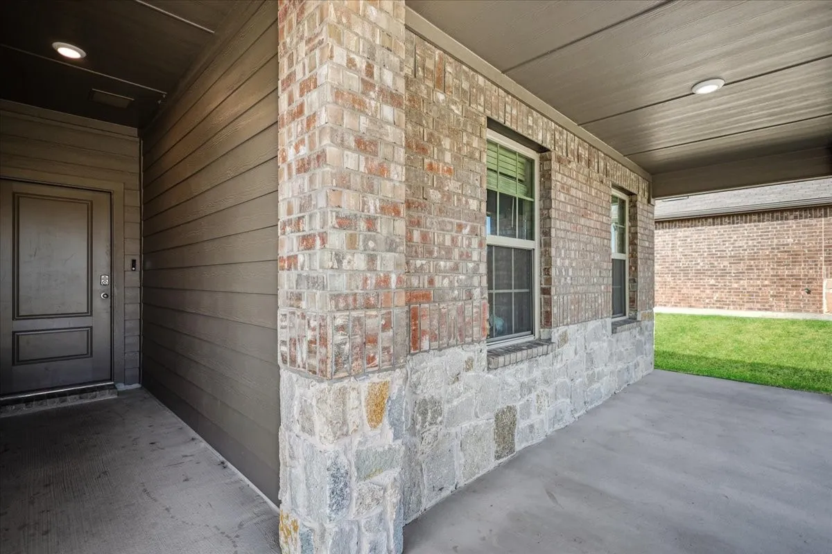 Covered concrete patio featuring brick and stone veneer exterior