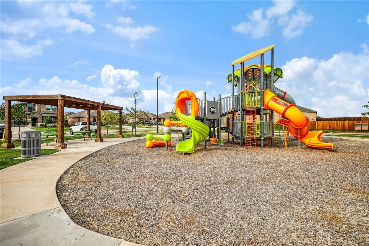 Community playground with multi-level play structures, slides, and a nearby pergola