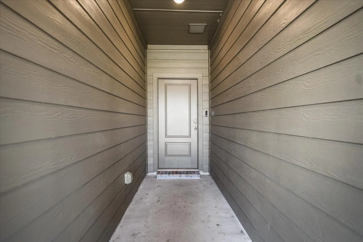 Recessed entryway with plank siding, a panel door, and an overhead light fixture