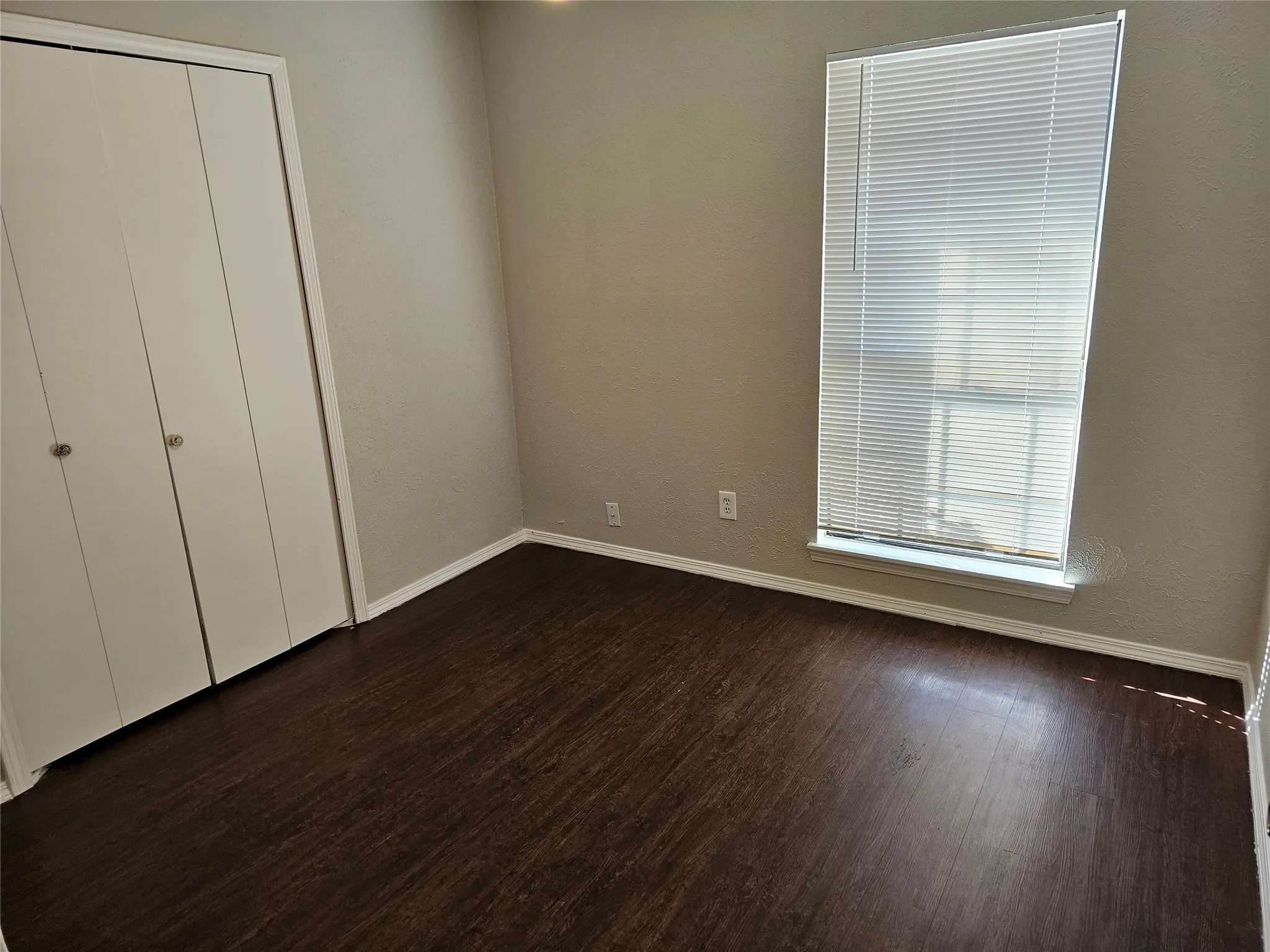 Wood-finish flooring with neutral wall tones and a window featuring blinds