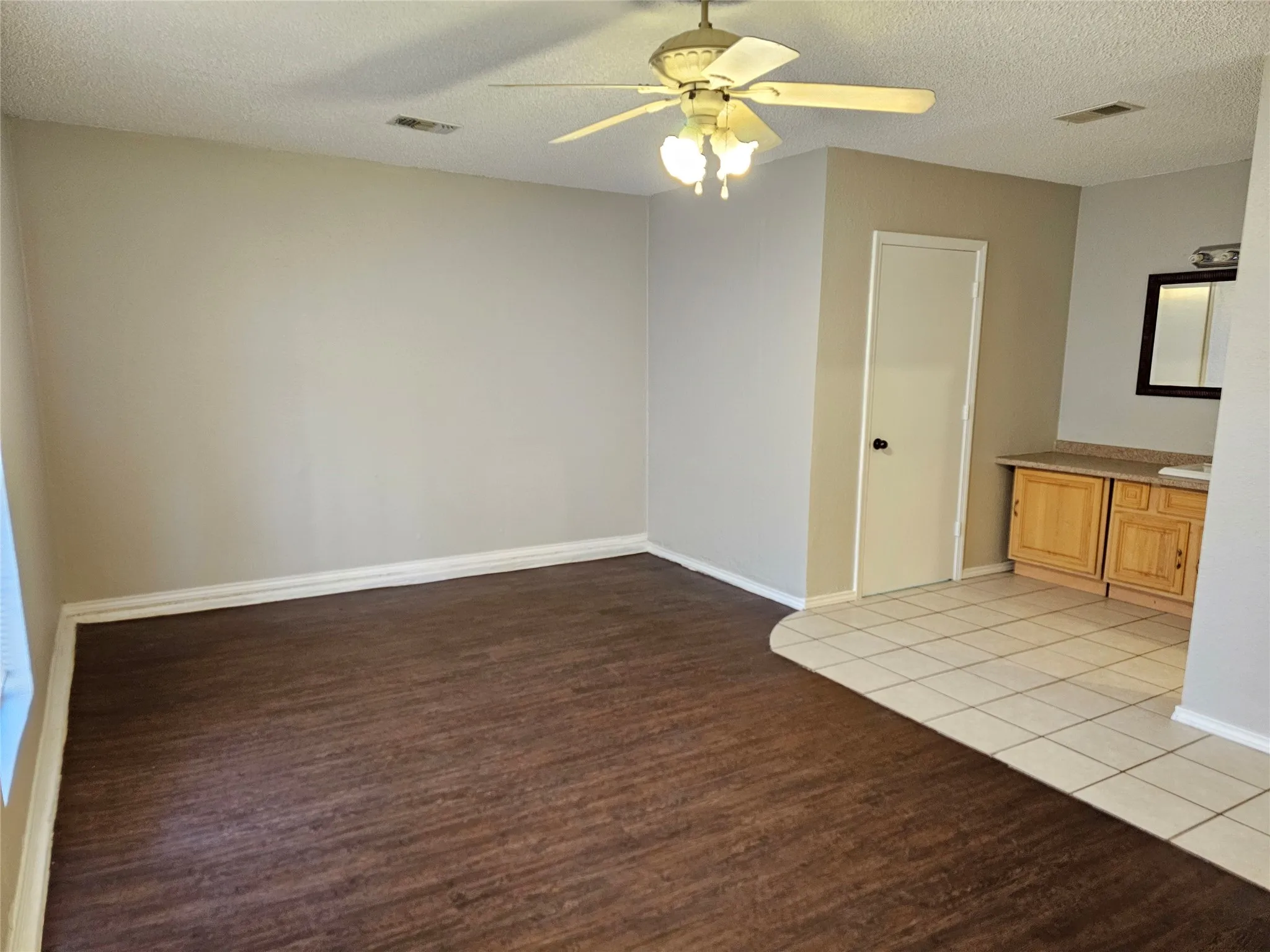 Wood-finish flooring, ceiling fan, built-in cabinetry with countertop, tiled flooring, and a wall-mounted mirror