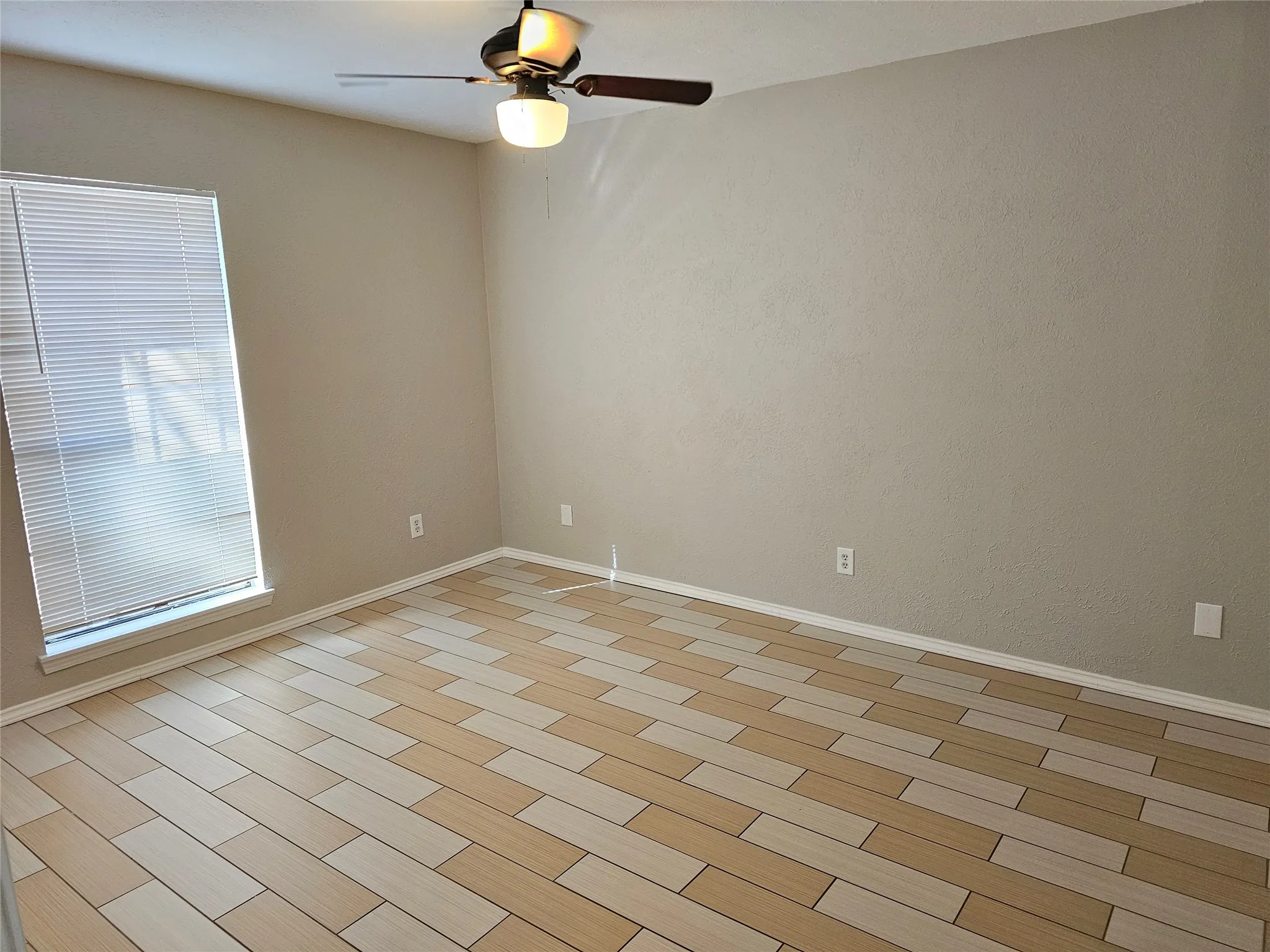 Rectangular window with blinds, wood-finish flooring, and a ceiling fan with integrated lighting