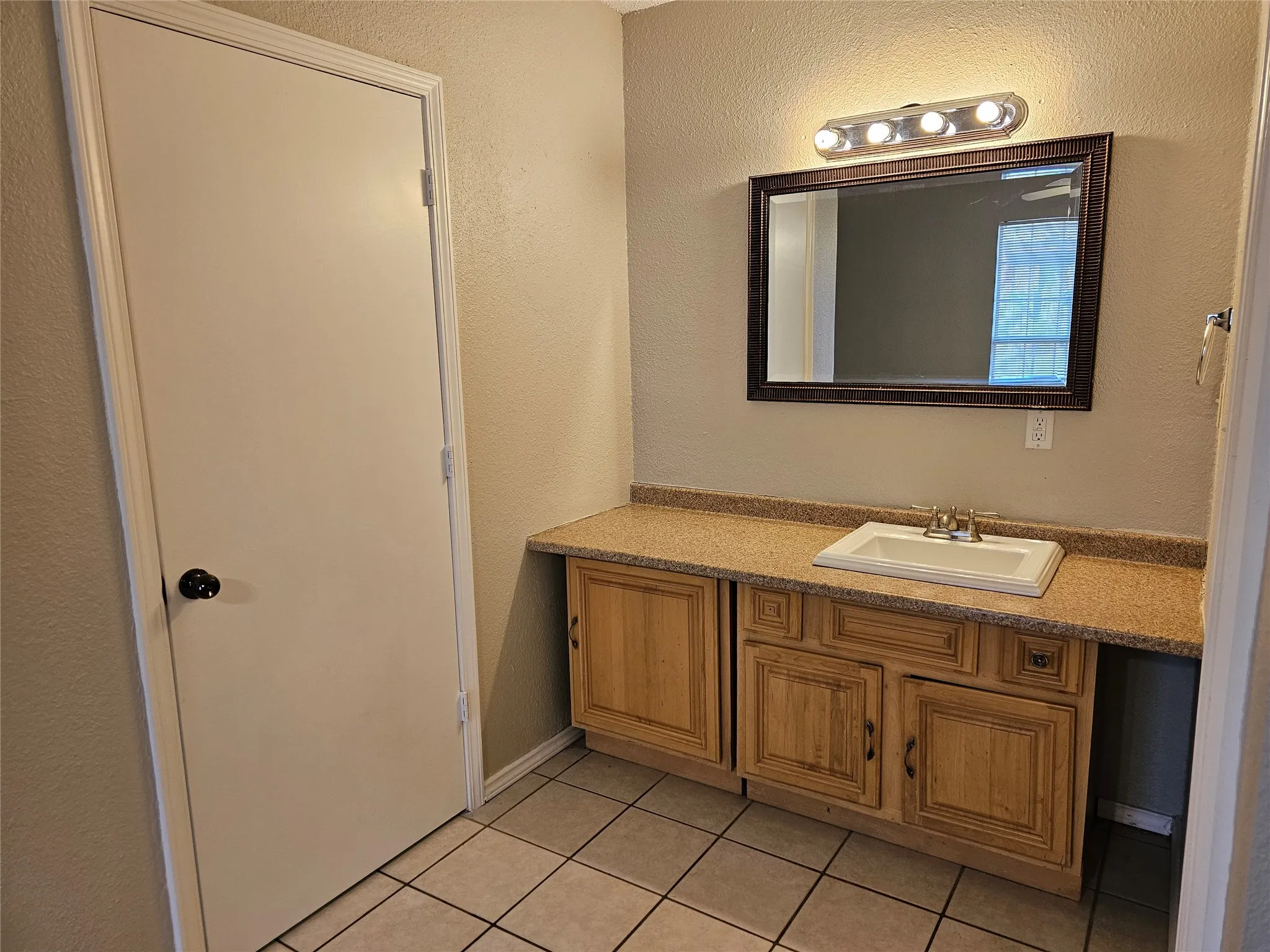 Vanity with wood-finish cabinetry, integrated sink, and granite-finish countertop