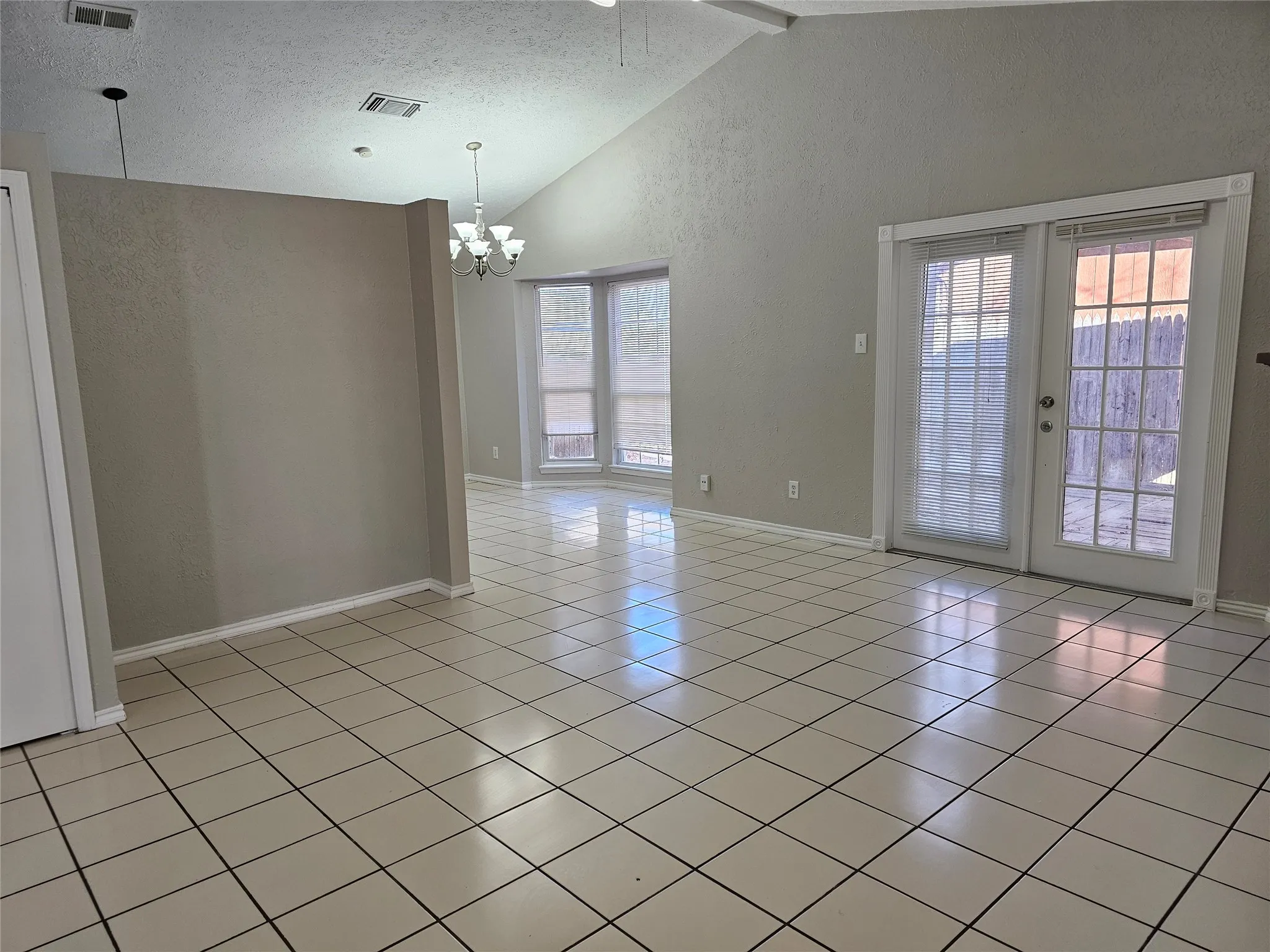 Tiled flooring throughout, vaulted ceiling, bay windows, and double French doors with a transom window