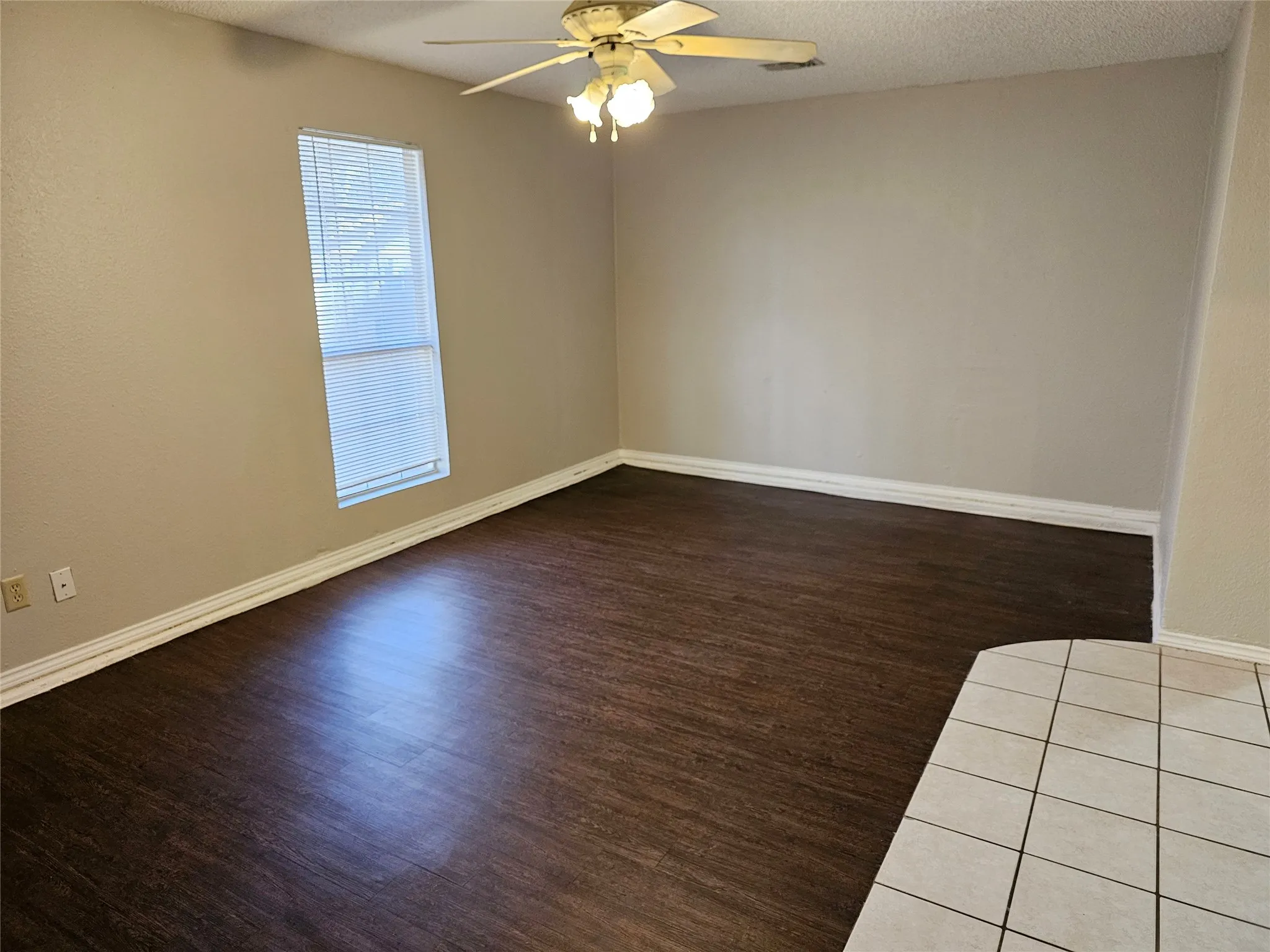 Neutral wall paint, wood-finish flooring, white trim, ceiling fan light fixture, and a window with blinds