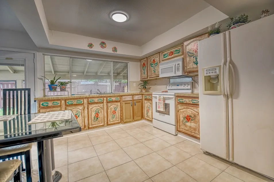 Kitchen featuring tile flooring, white appliances, and a window over the sink