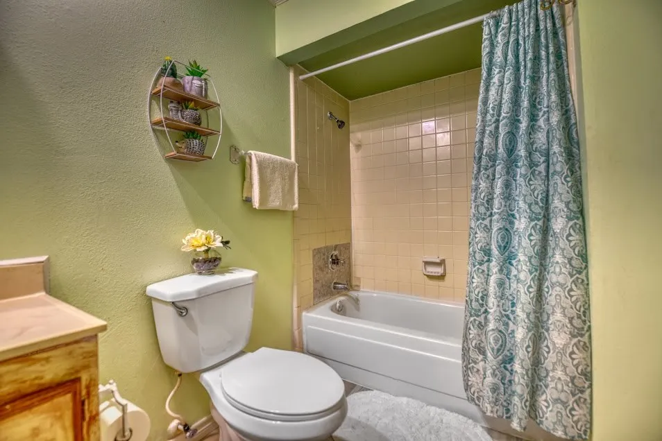 White toilet with a built-in toilet paper holder and a white bathtub with tile surround
