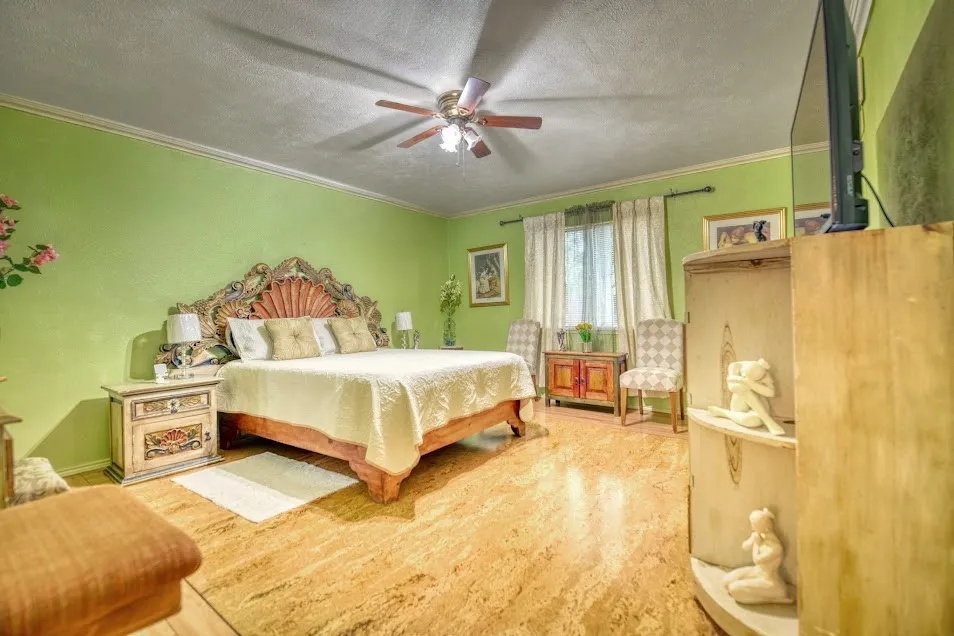 Recessed ceiling with a ceiling fan, crown molding, and wood-finish flooring