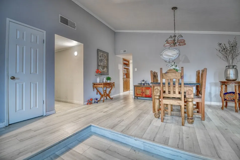 Light-toned wood-finish flooring, accent wall with vaulted ceiling, and recessed entryways